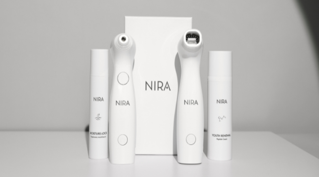 White nira skincare product set with sleek minimalist cylindrical bottles and two handheld devices for skincare giveaways