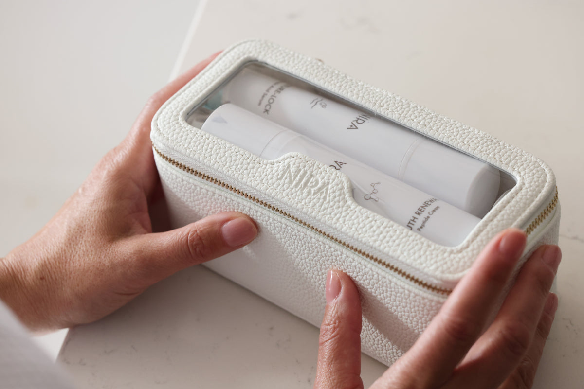 Travel case with NIRA Skincare products neatly arranged on a bathroom counter for easy on-the-go skincare.
