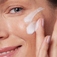 Woman applying renewing face cream with peptides after laser treatment