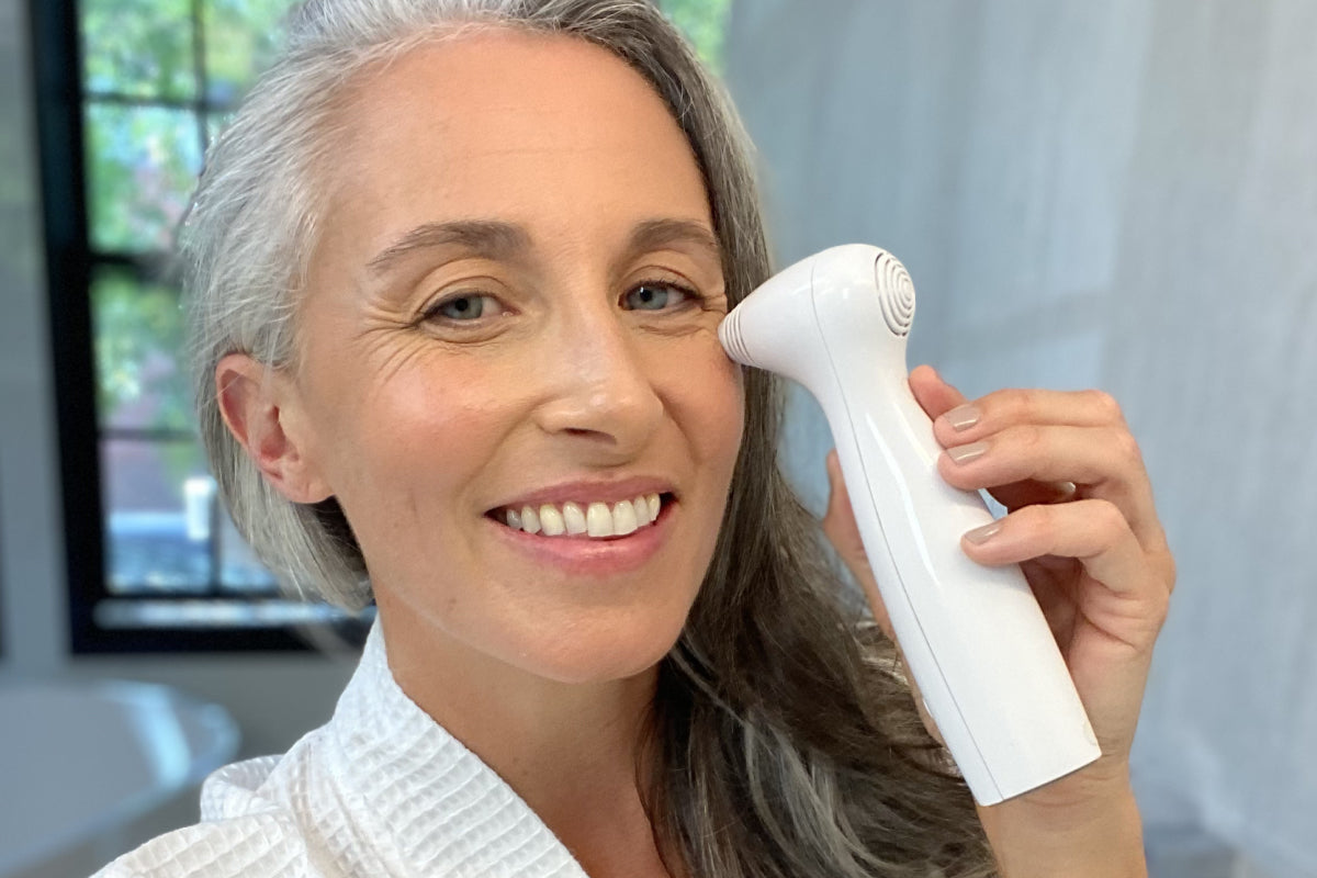 Close-up of an older woman applying the NIRA at-home laser device to the fine lines beneath her eye.