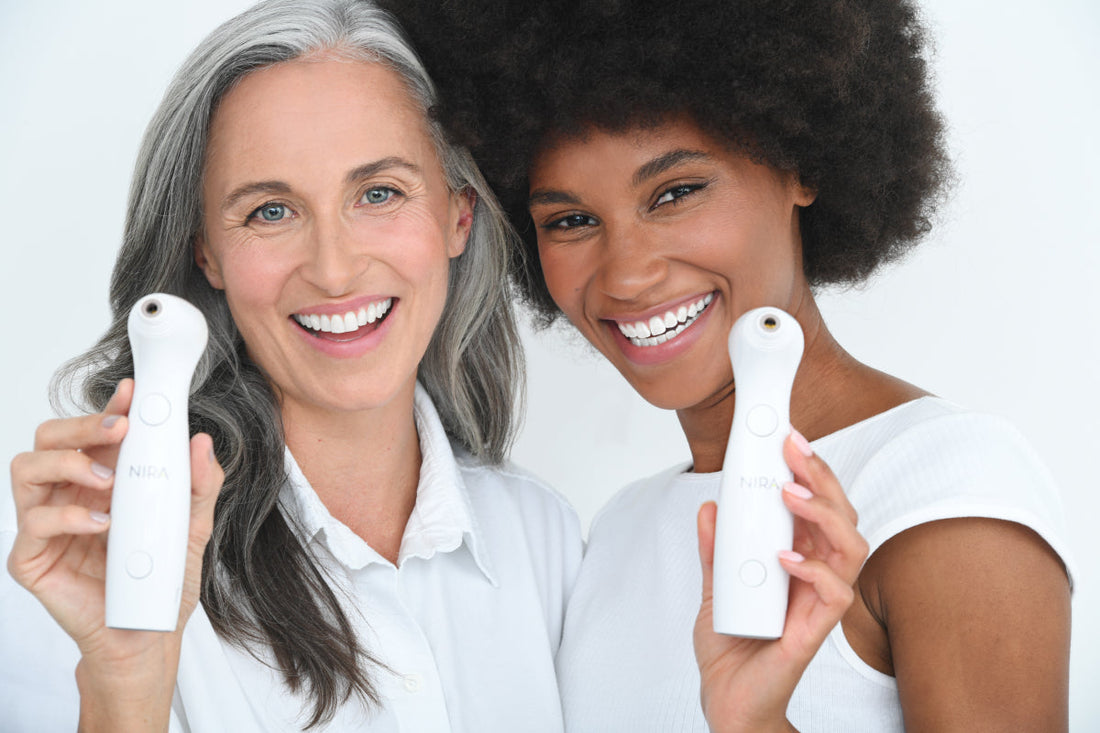 Two smiling women, each holding a Nira Skin Laser, representing effective anti-aging treatment for all skin tones and mature skin.