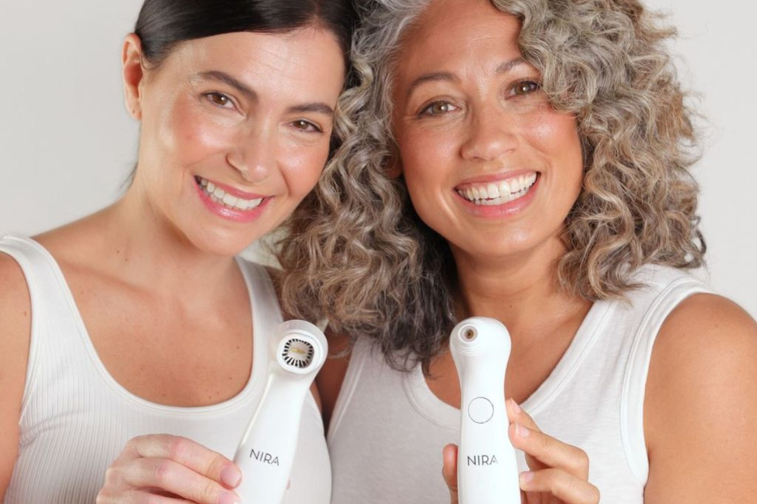 Two people of different ages holding a Nira at-home laser device, smiling and showing glowing, radiant skin together.