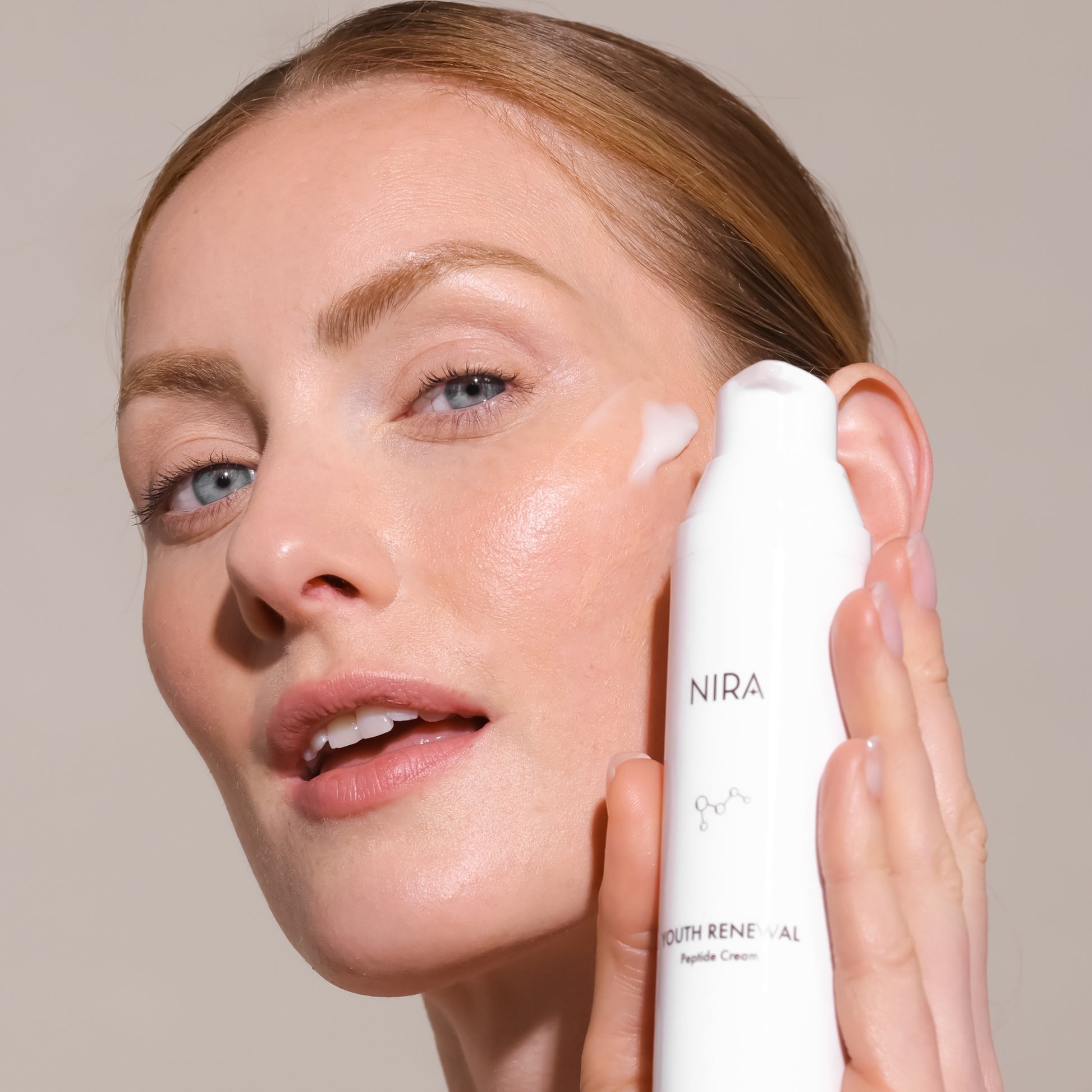 Woman using NIRA Youth Renewal Peptide Cream on her face