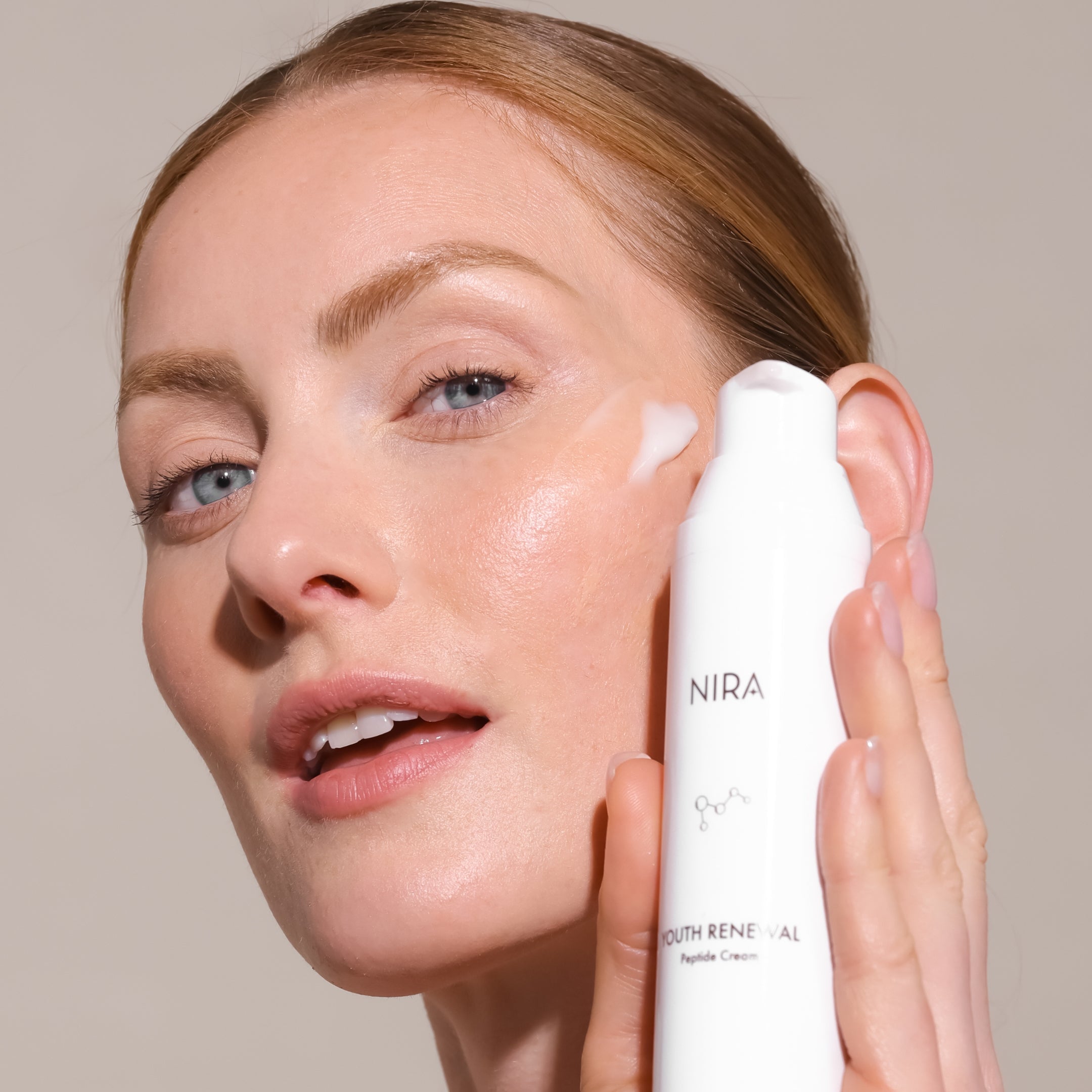 Woman using NIRA Youth Renewal Peptide Cream on her face