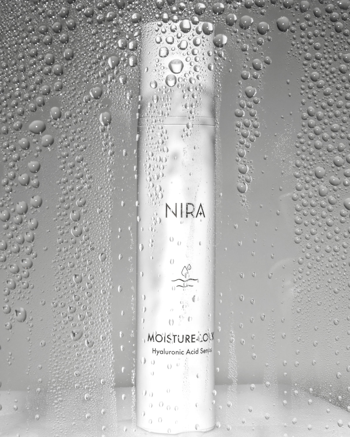 A sleek white cylindrical bottle of NIRA Moisture-Lock hyaluronic acid serum with minimalist black text and water droplet logo