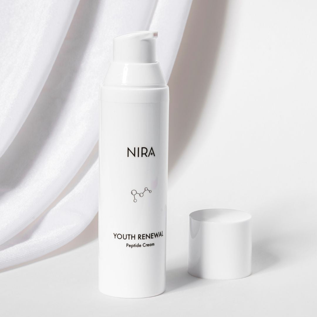 White cylindrical bottle of nira youth renewal peptide cream with matching white pump and minimalist black labeling