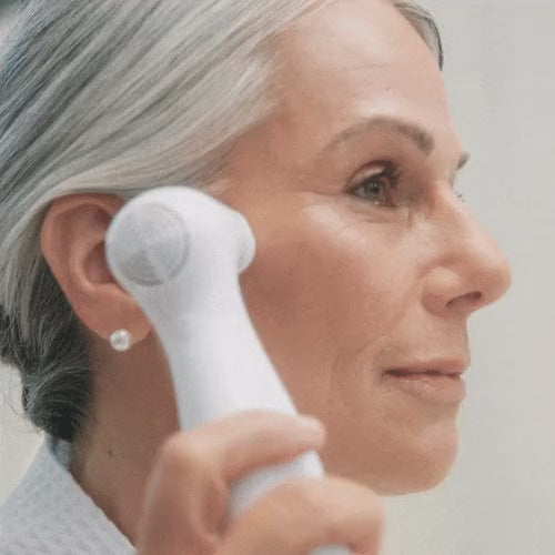 Woman moving the NIRA Pro 3 laser across her cheek during a treatment