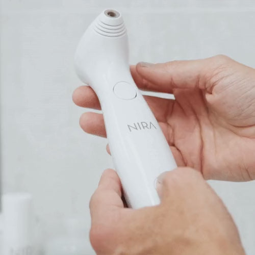 Hands holding the NIRA Precision laser, showing the button used to set the power level
